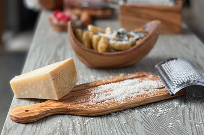 Block of Parmesan cheese on a wooden board with a grater