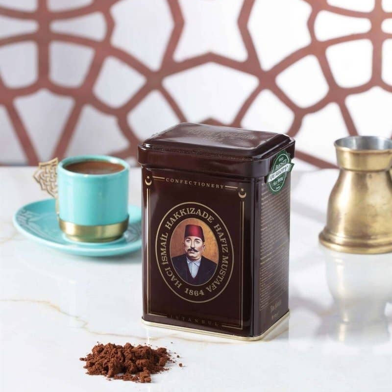 Coffee canister with a portrait on a marble surface with a decorative wall in the background