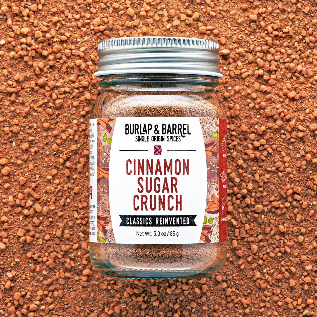 A glass jar of Burlap &amp; Barrel Cinnamon Sugar Crunch spices, featuring a white label and a silver metal lid