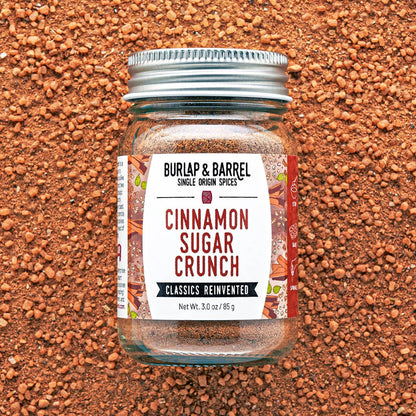A glass jar of Burlap &amp; Barrel Cinnamon Sugar Crunch spices, featuring a white label and a silver metal lid