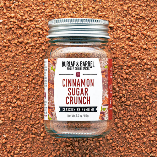A glass jar of Burlap & Barrel Cinnamon Sugar Crunch spices, featuring a white label and a silver metal lid
