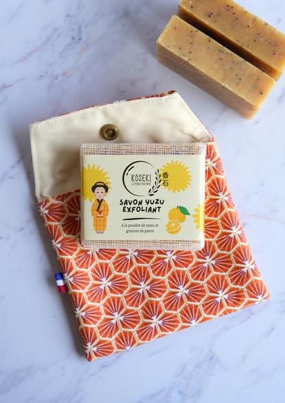 Two bars of soap on a patterned fabric with a box labeled &