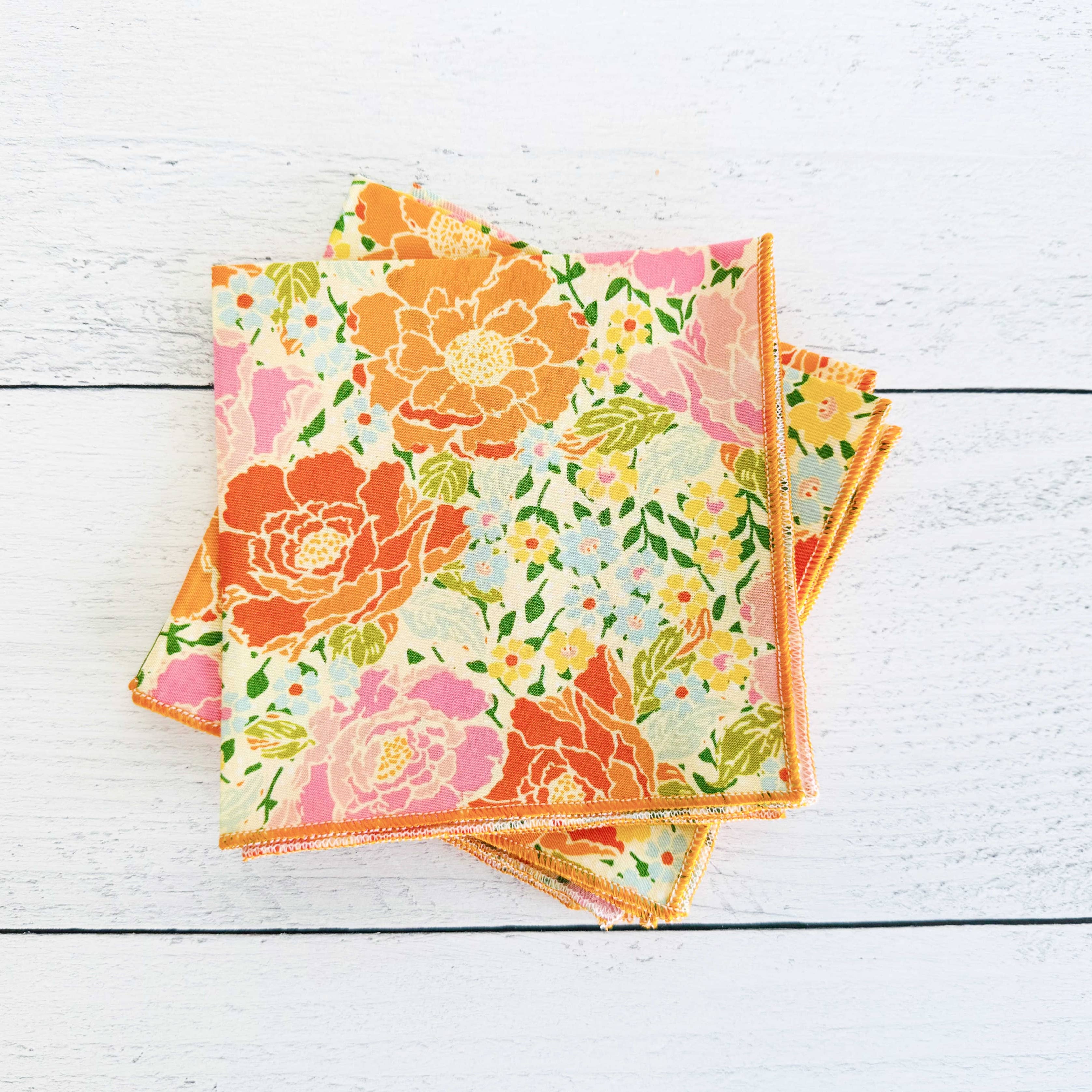 Set of floral-patterned napkins on a white wooden surface