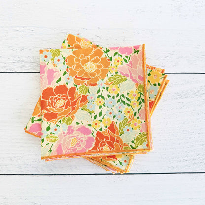Set of floral-patterned napkins on a white wooden surface