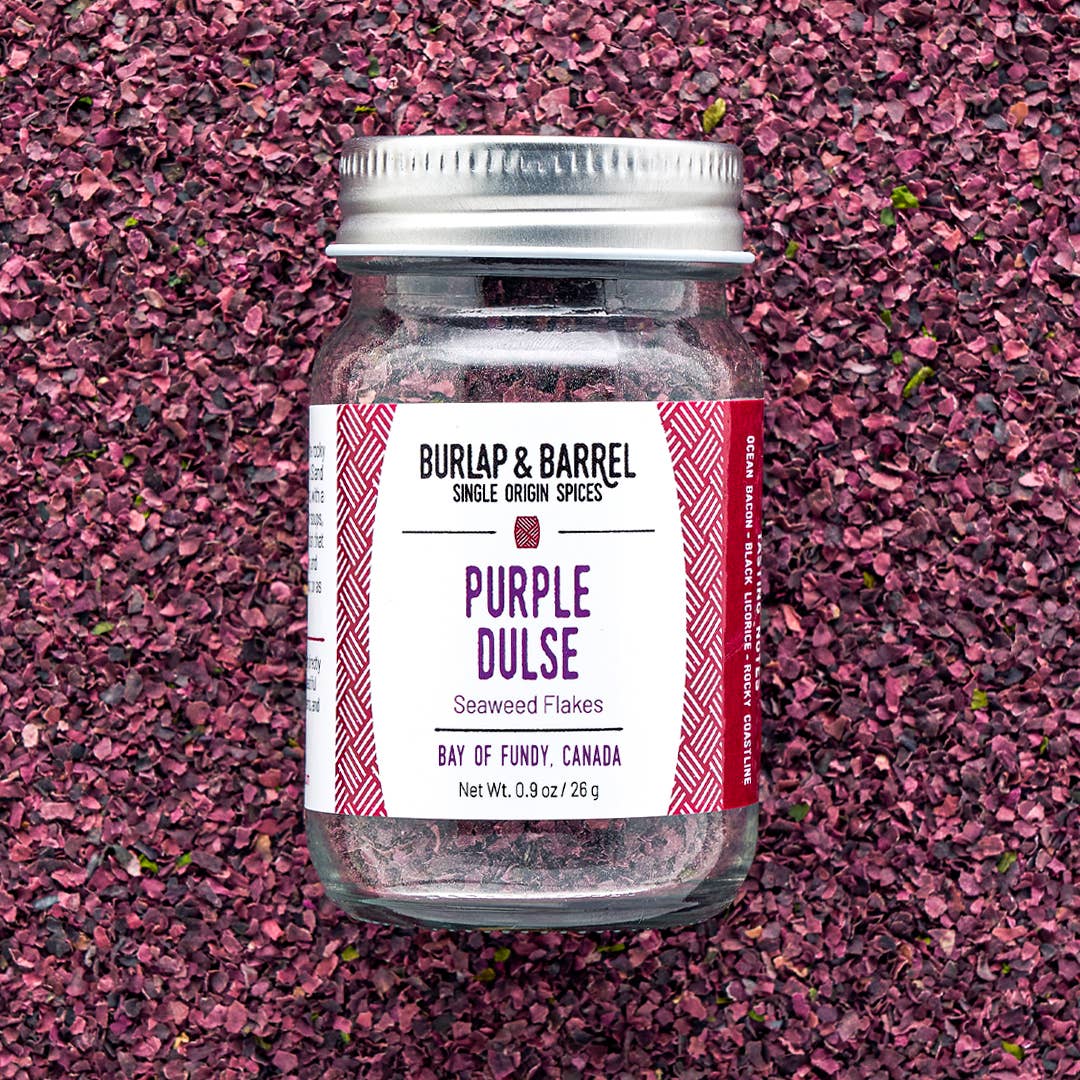 Jar of Burlap &amp; Barrel Purple Dulse flakes on a pinkish-purple textured background