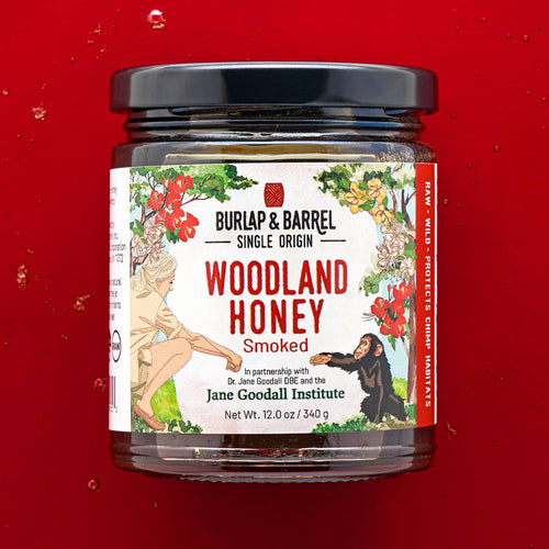 Jar of Burlap & Barrel Woodland Honey on a red background
