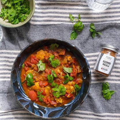  bowl of curry with kasuri methi masala on a striped fabric background