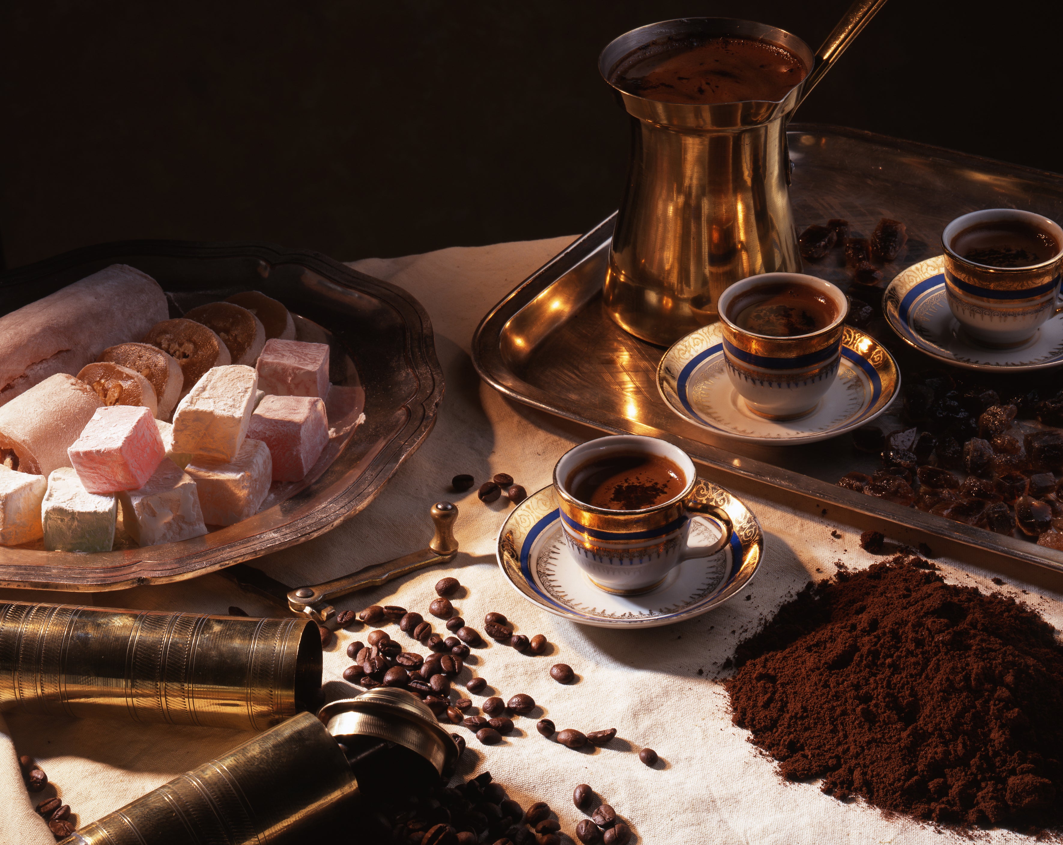 Café setting with coffee cups, grinder, and Turkish delight on a dark background