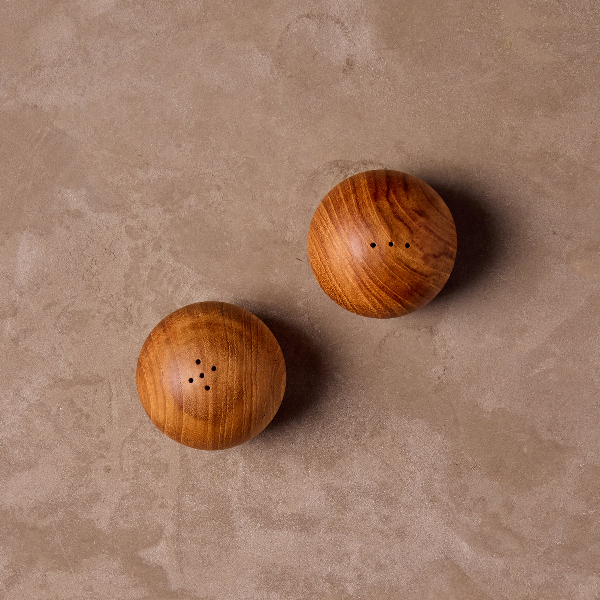 Top view of two teak wood salt and pepper shakers on a beige surface
