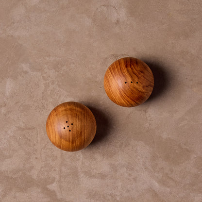 Top view of two teak wood salt and pepper shakers on a beige surface